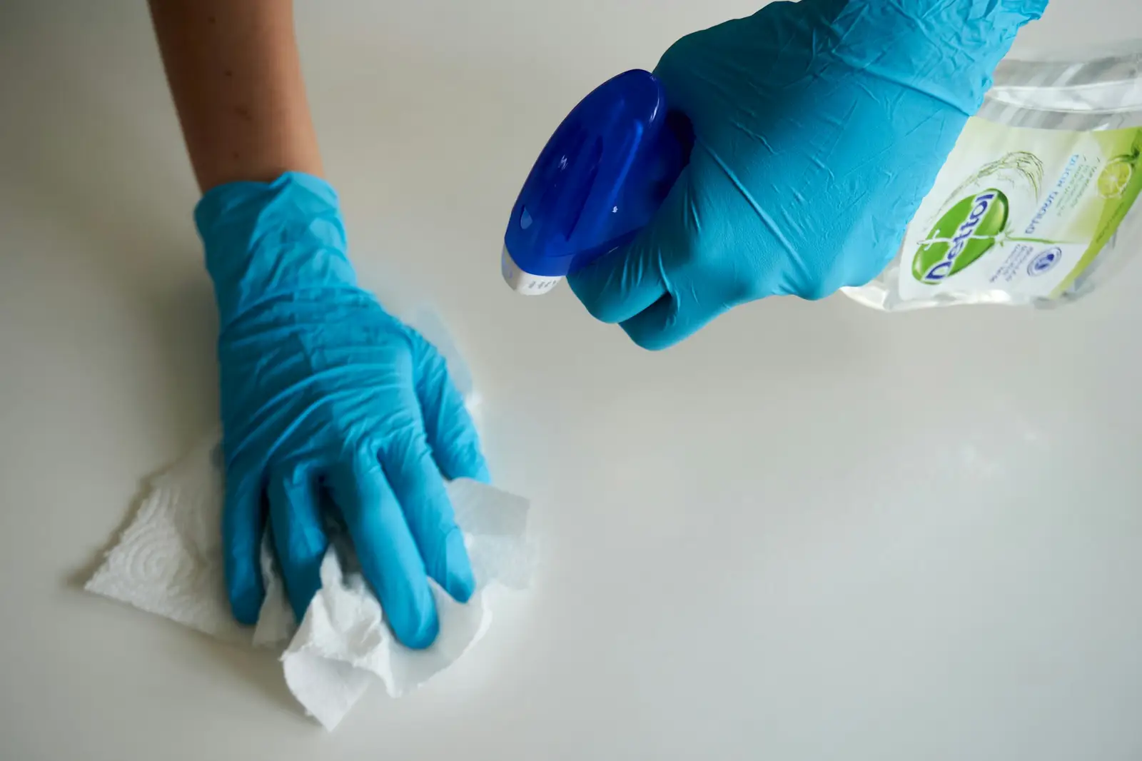 Cleaner in blue gloves wiping a kitchen worktop D&A Cleaning Ltd