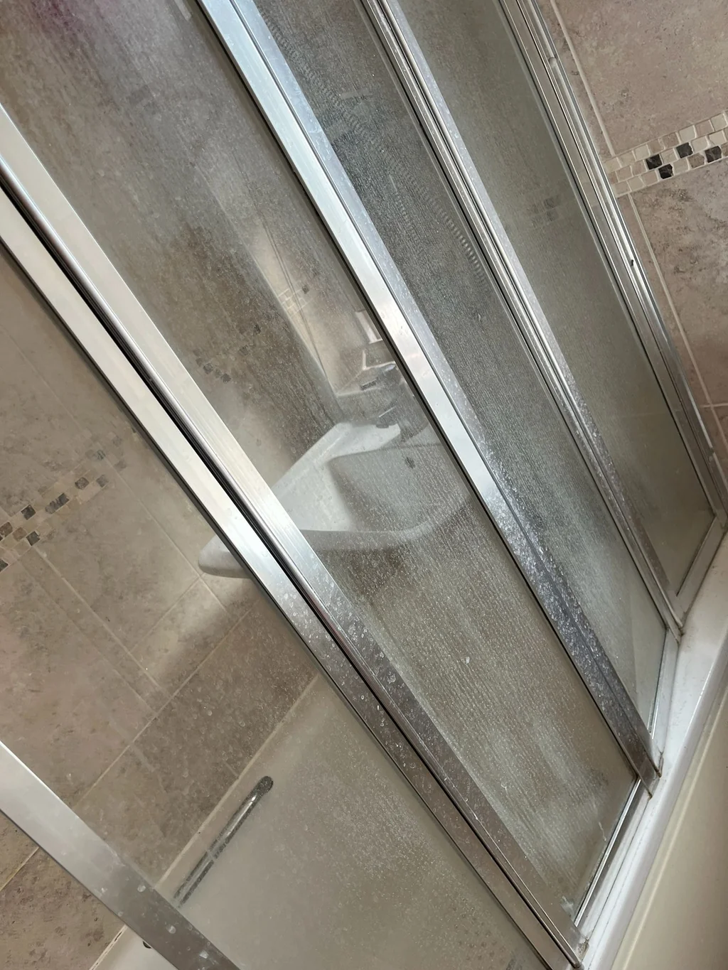 Bath shower doors coated in limescale before cleaning