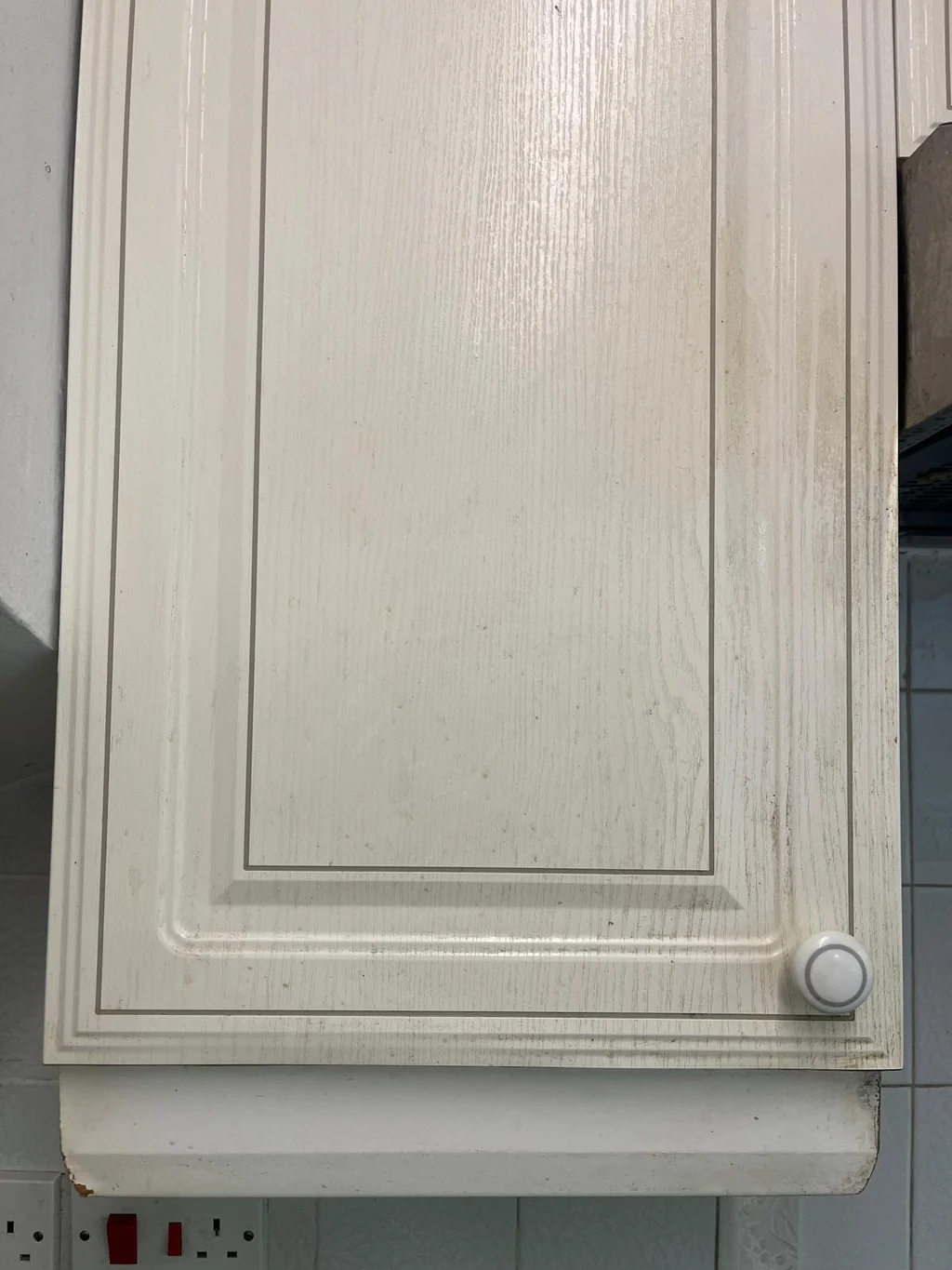 White kitchen cupboard door yellowed with grease before cleaning