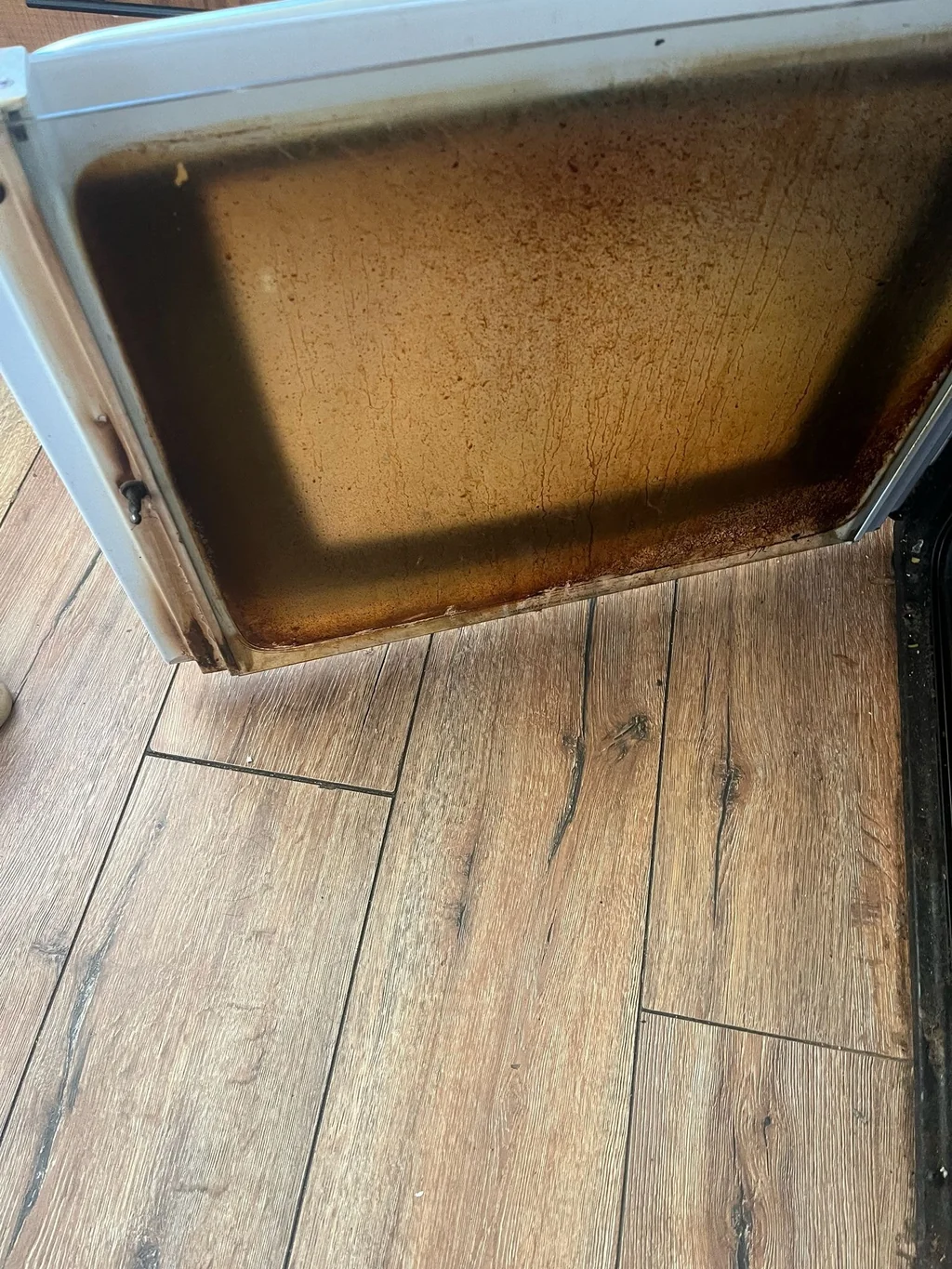 Oven door glass coated in baked-on grease before cleaning