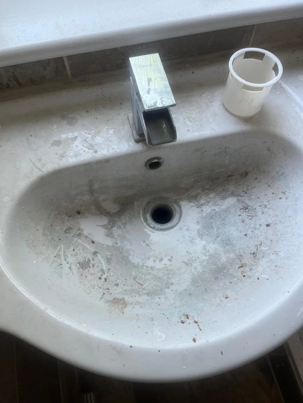 Round basin stained with limescale and dirt before move-in clean