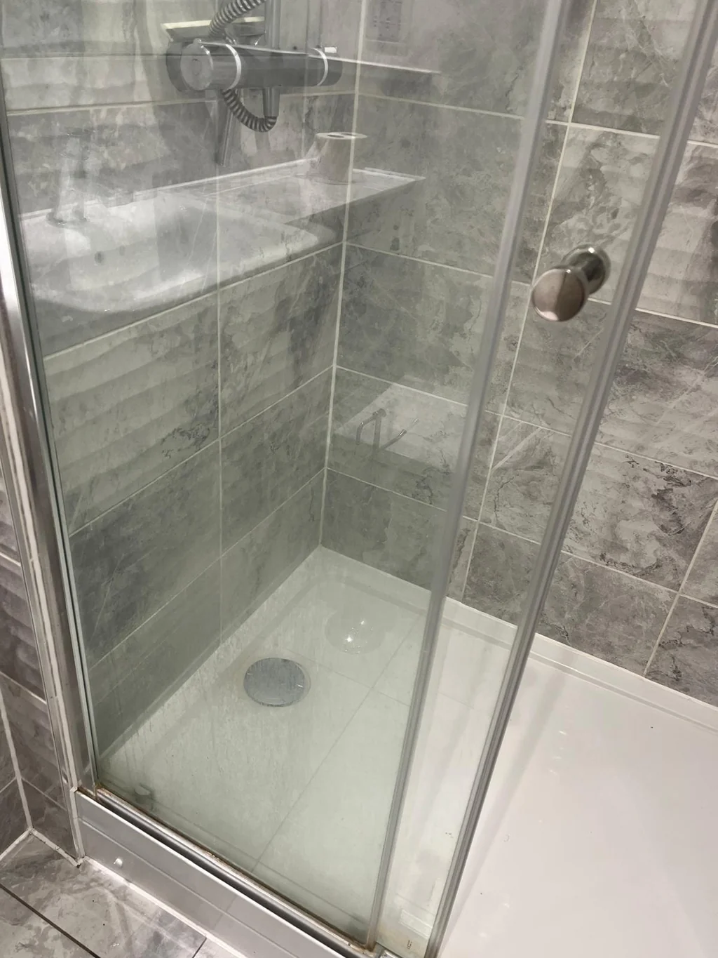 Glass shower enclosure clouded with limescale before descaling
