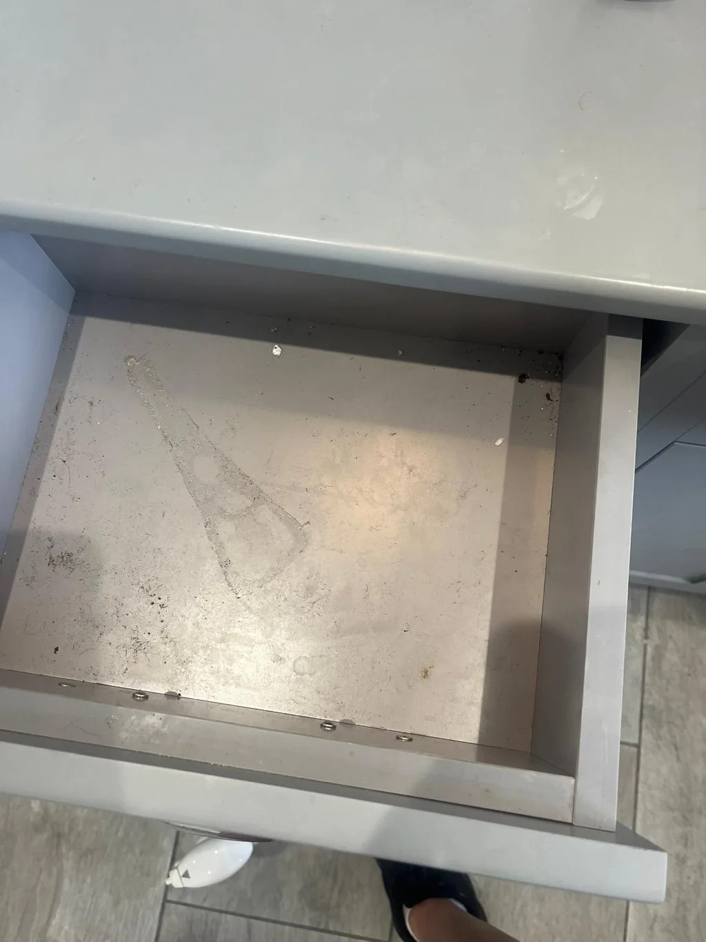 Bathroom vanity drawer full of dust and grime before cleaning